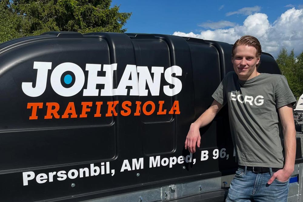 Elev som står vid Johans trafikskolas bil